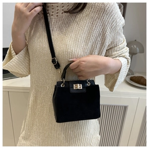 Detail of black faux suede crossbody bag featuring gold metal clasp and leather strap