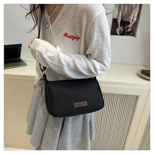 Detail of minimalist black canvas crossbody bag with adjustable strap and leather patch