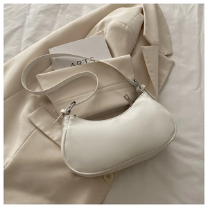 Detailed shot of white hobo bag with silver zipper and smooth finish on beige blazer