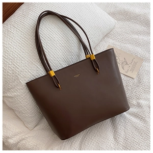 Deep brown matte PU tote bag detail with golden metal buckles and logo on white fabric