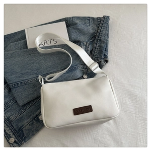 Détail d'un sac bandoulière blanc en PU avec étiquette marron et large sangle