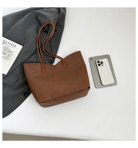 Flat lay of brown pebble leather tote bag with thin straps and a Matisse magazine