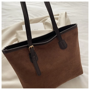 Macro detail of dark brown suede tote bag with leather strap and gold buckle