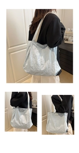 Detail of light blue nylon tote bag showing textured fabric and fashion label accent