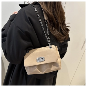 Détail du sac beige plissé avec chaîne, strass brillants et fermoir rotatif argenté