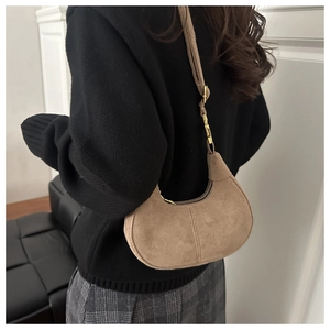 Détail du sac croissant en daim kaki avec boucles en bambou doré et coutures élégantes