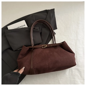 Macro detail of dark brown suede tote bag featuring thin straps and gold buckle accent
