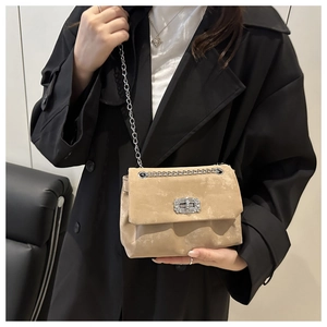 Detail of beige suede crossbody bag with elegant silver chain and sparkling crystal lock