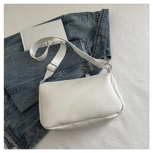 Detailed close-up of white minimalist square bag with adjustable shoulder strap and silver buckle
