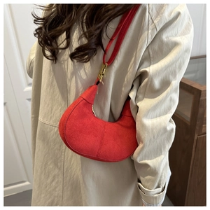 Détail du sac hobo rouge en forme de croissant avec boucle dorée sur le mannequin