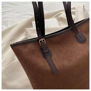 Close-up of brown suede tote bag featuring adjustable leather straps and metal buckles