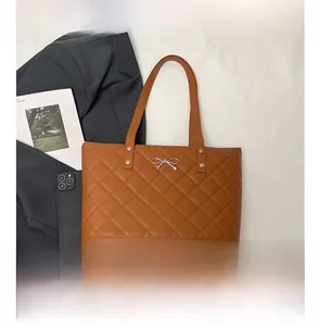 Detail of brown quilted tote bag with silver bow accent and business style props