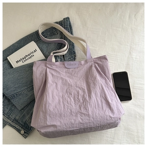 Top view of a purple pleated tote bag with stylish patchwork handles and lifestyle props