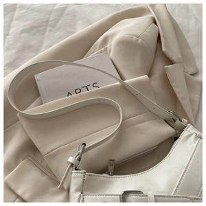 Close-up of white PU leather crescent bag with adjustable silver buckle strap detail