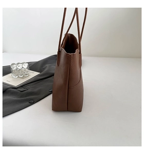 Side view of brown textured leather tote bag showing spacious interior and slender straps