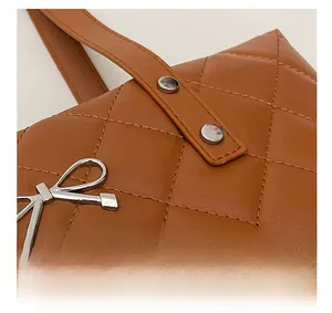 Macro detail of caramel brown quilted leather with silver bow hardware on a tote bag