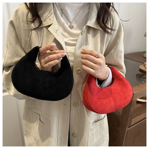Detail of red and black suede crescent handbags with soft matte texture and handles