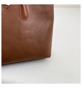 Close-up of brown lychee grain leather handbag showing fine stitching and texture detail