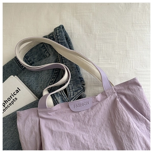 Detail of light purple pleated tote bag with cream woven straps and fashion patch label