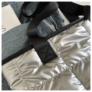 Detail of silver metallic puffer tote with diamond quilting and reinforced strap stitching
