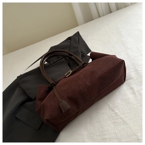 Détail d'un sac cabas en daim marron foncé avec coutures fines et boucle en métal doré