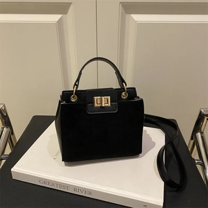 Minimalist black matte crossbody bag with golden square lock on a white studio background