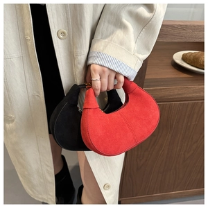 Detail of red and black suede dumpling bags held by a model in a retro setting