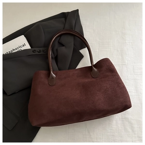 Vue à plat d'un sac à main bordeaux en daim avec anses lisses sur blazer gris chic