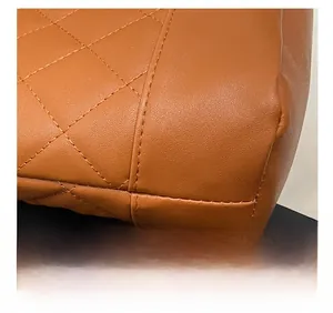 Macro detail of high-density stitching and quilted diamond pattern on brown leather tote bag