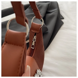 Dettagli di borsa marrone a pieghe con hardware argento e decorazione floreale in strass