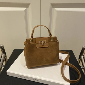Brown faux leather shoulder bag with gold twist lock on white books background