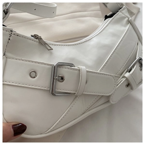 Detail of white leather shoulder bag featuring silver buckles and rivet craftsmanship