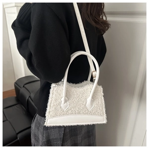 Detail of white plush faux fur handbag with smooth leather trim and long shoulder strap