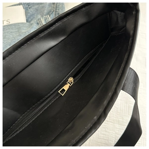 Close-up of black tote interior with golden zipper and durable nylon shoulder strap
