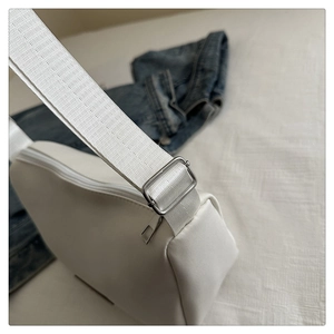 Detailed close-up of white crossbody bag showing nylon texture and silver metal buckle