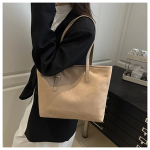 Detail of a large beige suede tote bag styled with a black suit for office commuting