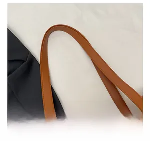 Close-up of brown quilted tote bag showing sturdy handles and metal ring hardware detail
