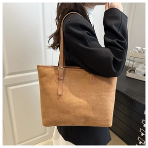 Close-up of brown suede tote bag featuring adjustable metal buckle on slim leather shoulder strap