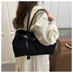 Detail view of the black suede tote bag with slim shoulder straps and gold hardware