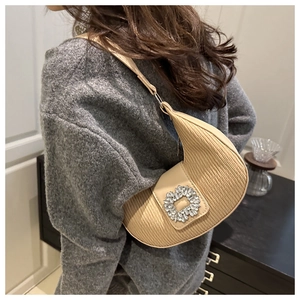 Dettaglio borsa a mezzaluna beige plissettata con grande fibbia rettangolare in strass