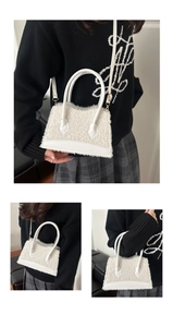 Detailed close-up of fuzzy white faux fur handbag with leather trim and gold hardware