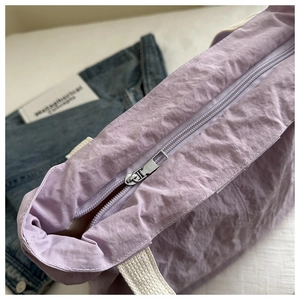 Detail of light purple tote bag with silver zipper and textured crinkle fabric surface