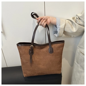 Detail of a large brown suede tote bag with adjustable dark leather shoulder straps