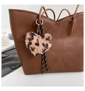 Leopard print heart plush charm with woven lanyard on a brown leather tote bag