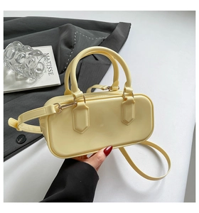 Detail of yellow glossy patent leather handbag with gold hardware and top handle