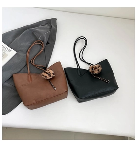 Detail of minimalist tote bags in black and brown with leopard print pom-pom charms