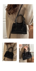 Detail of plush black faux fur and leather patchwork bag with golden metal hardware