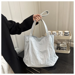 Détail du sac cabas bleu clair avec tissu froissé et logo de mode intégré