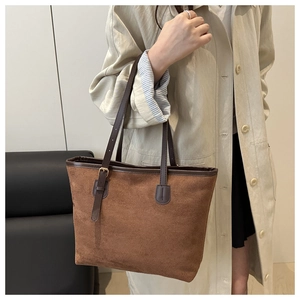 Detail of a large brown suede tote bag with a dark leather adjustable shoulder strap