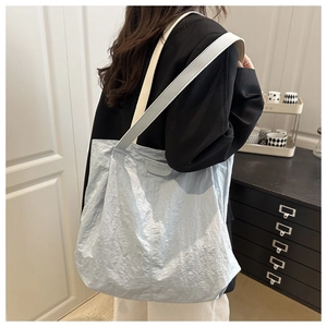 Detailed texture of light blue pleated tote bag with fashion leather patch and wide strap